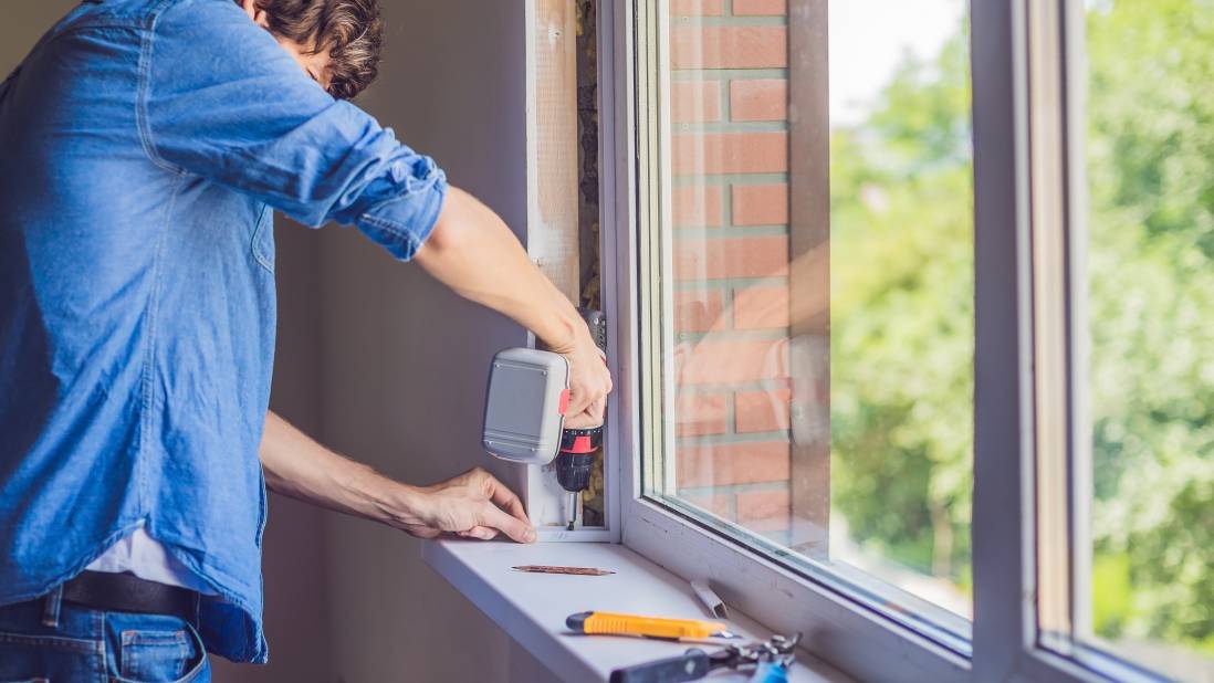 handyman repairing a window with tools