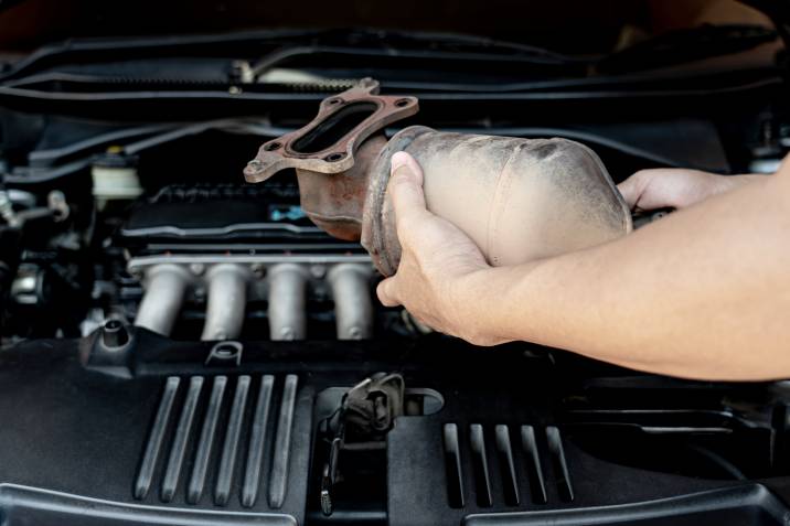 a mechanic replacing an old catalytic converter