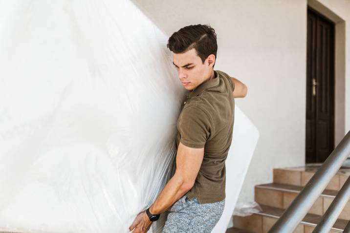 a man carrying a mattress