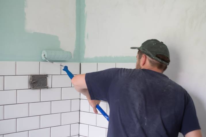 a man painting a house interior wall with a paint roller