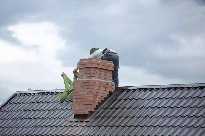 a worker repairing a brick chimney
