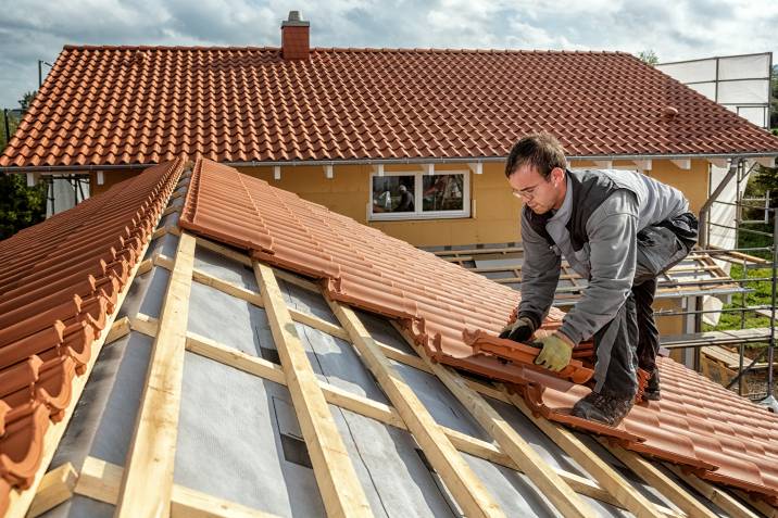 a roofer installing clay roof tiles