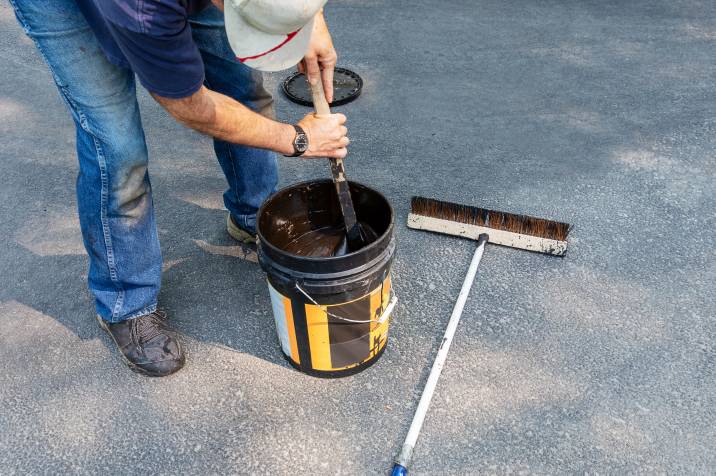 a man mixing sealant for the asphalt driveway