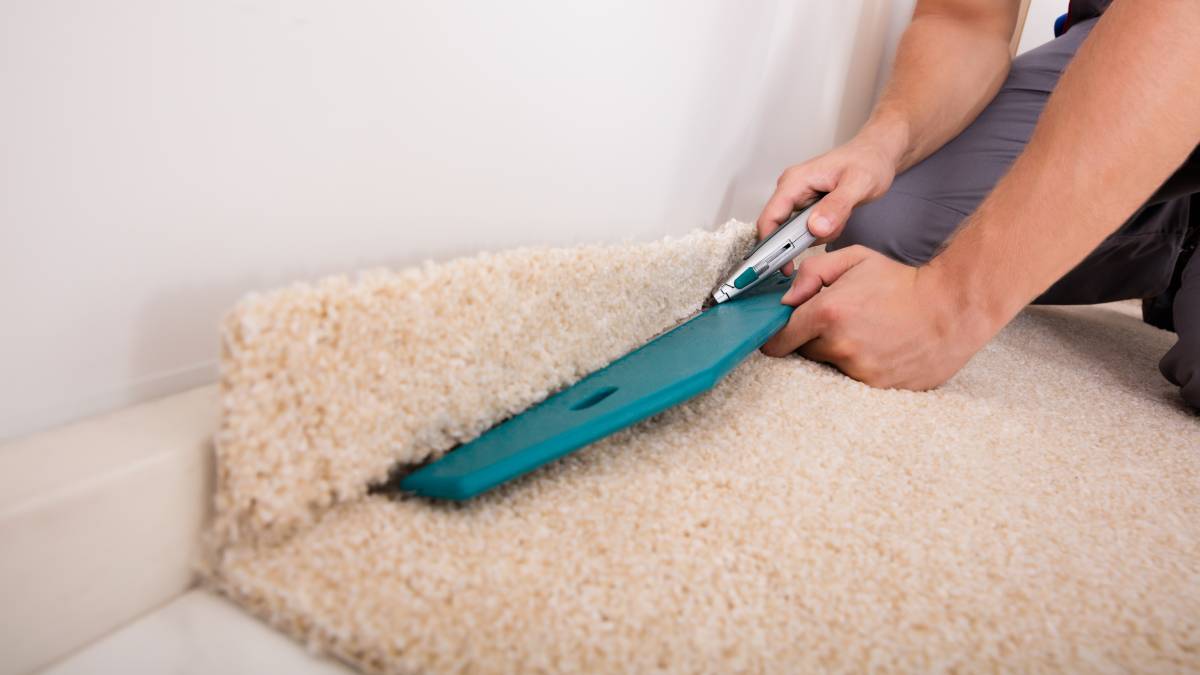 a worker installing floor carpet in a room
