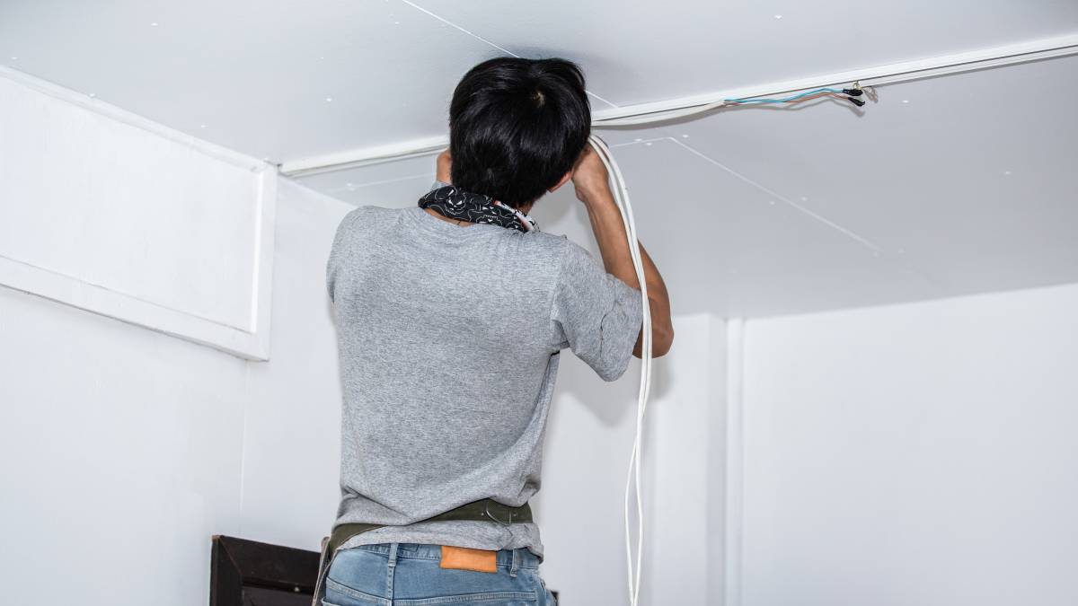 electrician installing electrical wires on ceiling