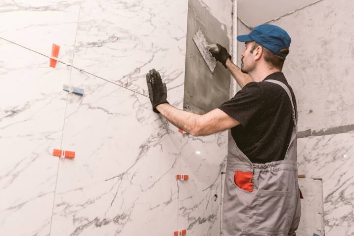 a handyman installing tiles on a renovated bathroom wall