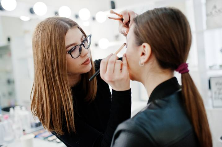 makeup artist applying eyeshadow to a woman