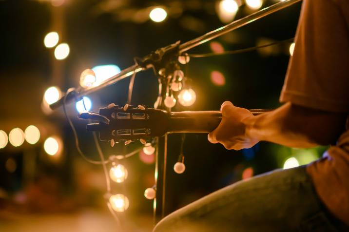 man plays acoustic guitar on an outdoor concert