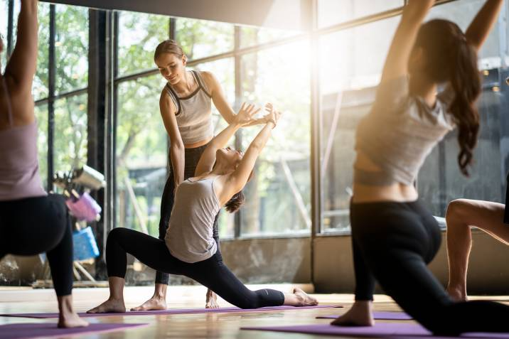 yoga teacher adjusting a student in class