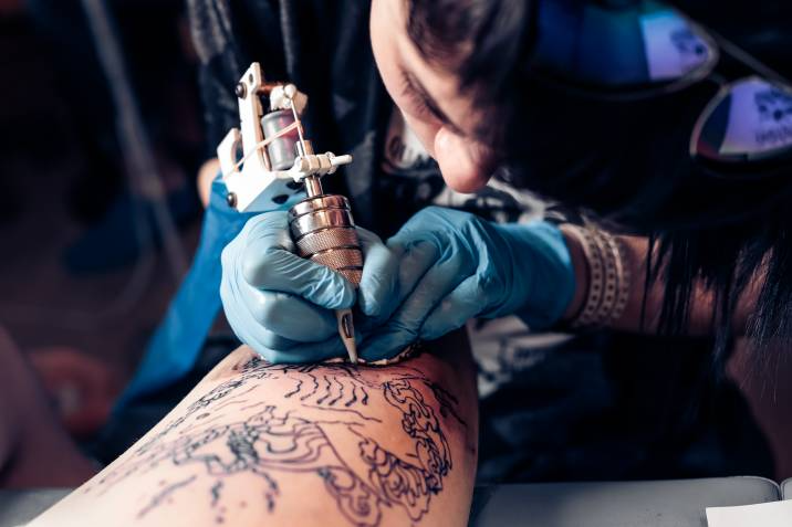 tattoo artist inking a person's arm