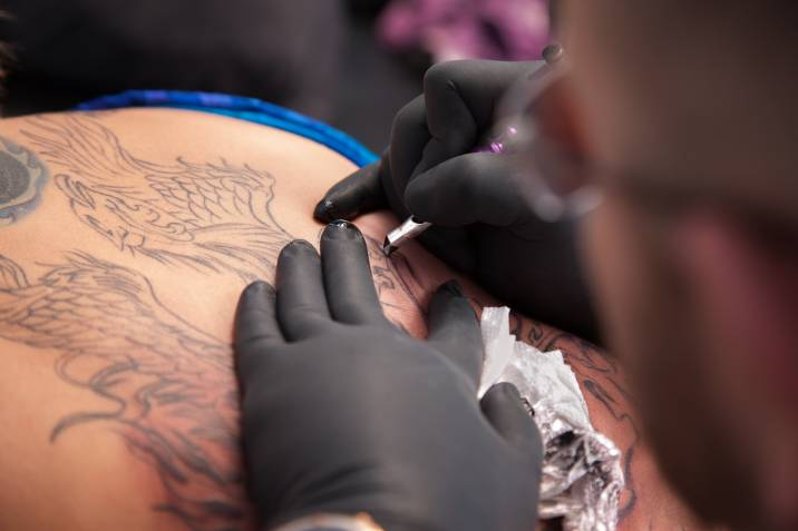 tattoo artist inking a person's back