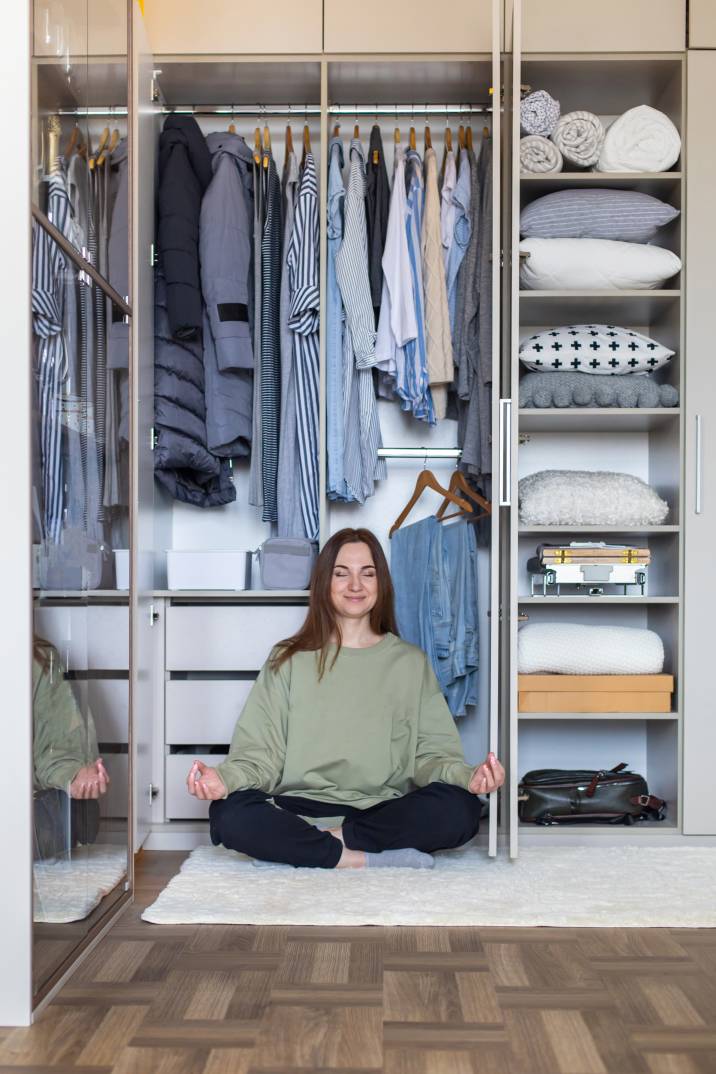 a woman sitting beneath neatly hung clothes