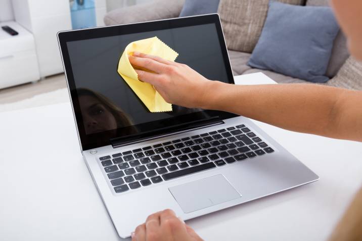 wiping laptop screen to clean dust