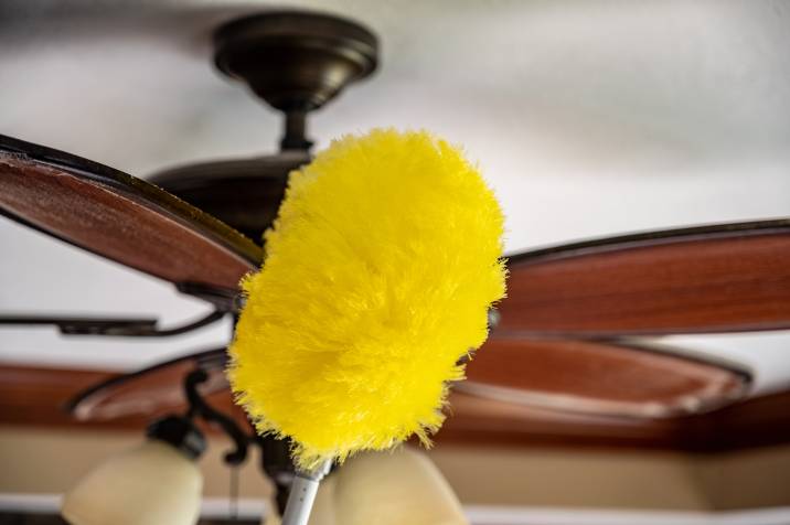 dusting a ceiling fan with wand feather duster