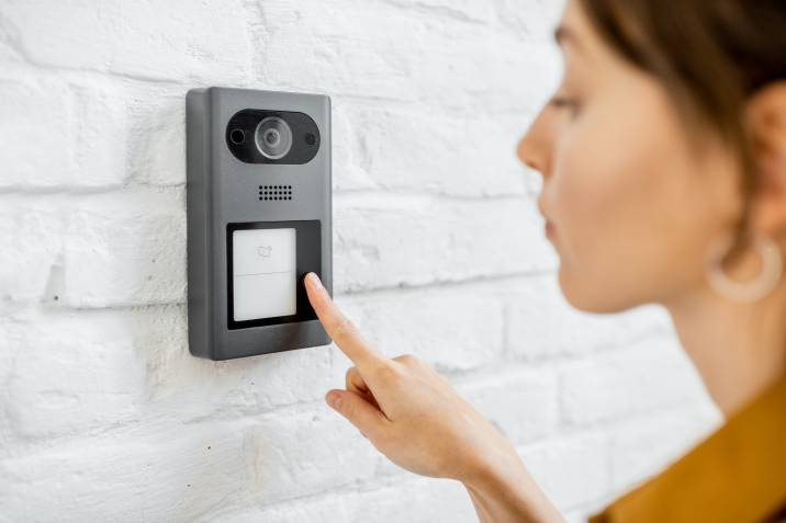 woman ringing a doorbell intercom