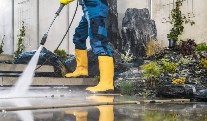 person using a pressure washer on the pavement