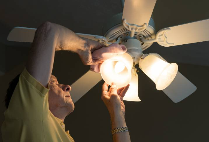 man attaching light bulbs on a ceiling fan