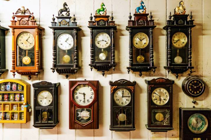 rows of pendulum clocks on a wall