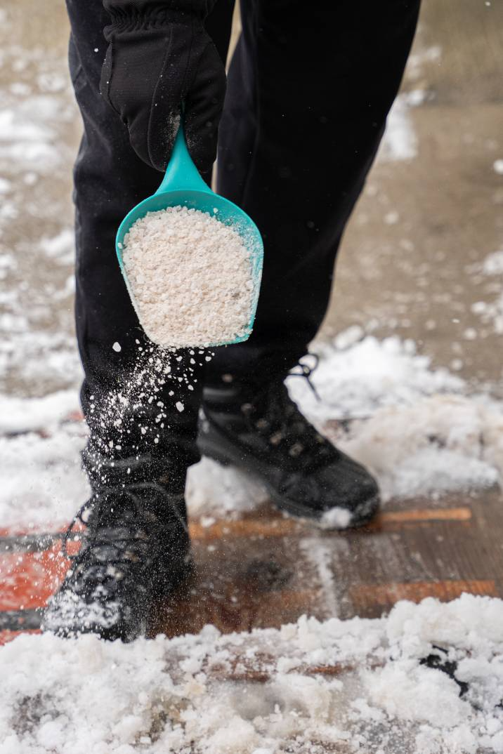 a man using rock salt to melt snow