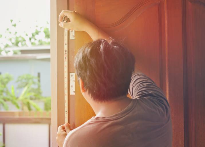 man measuring the length of his door frame