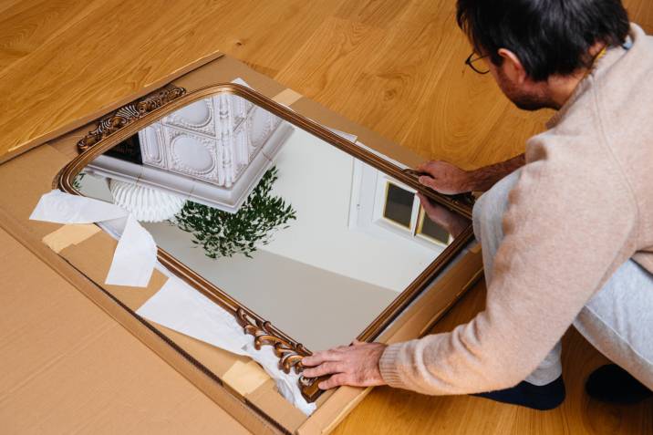 Man unboxing a mirror at his new home