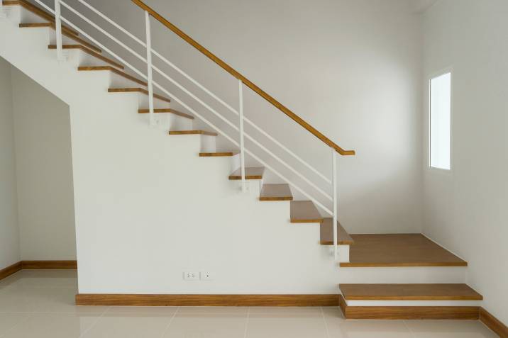 Side view of modern wooden stairs with freshly painted high wall