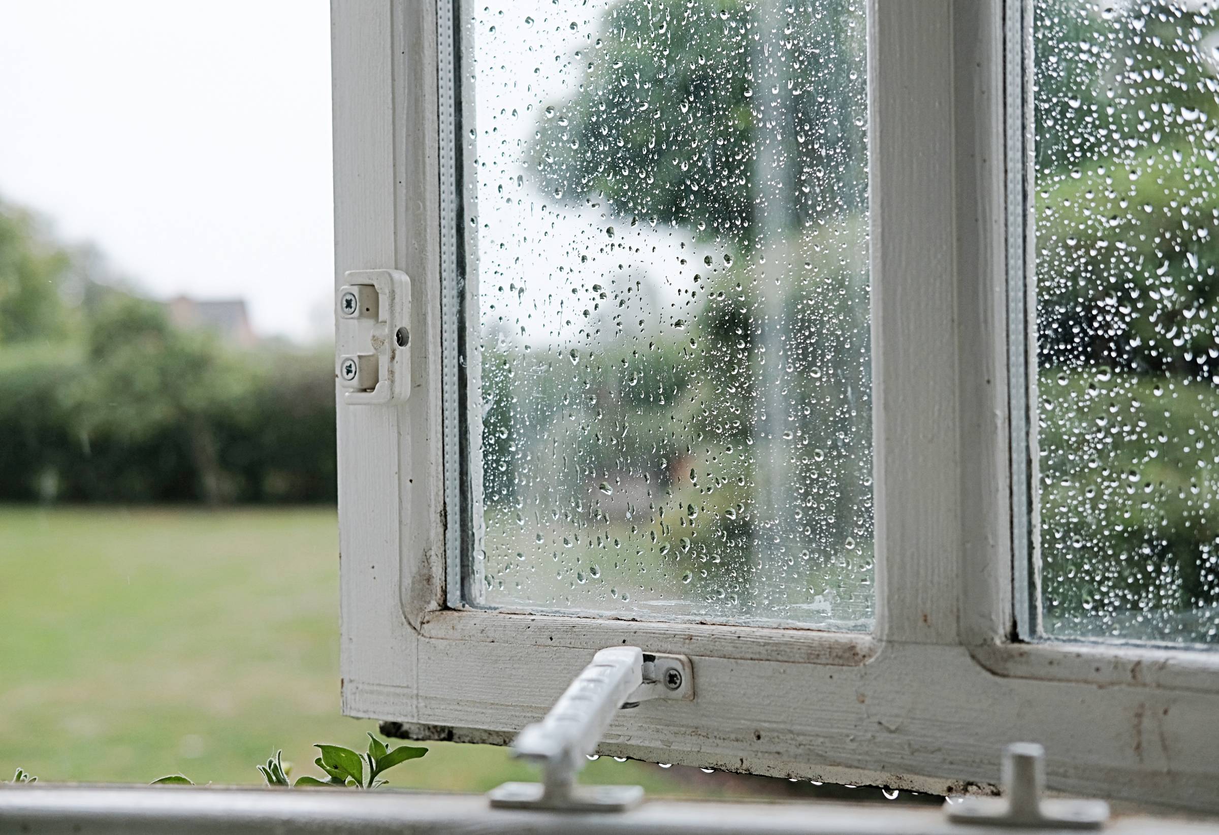 an unlocked window wet with rain