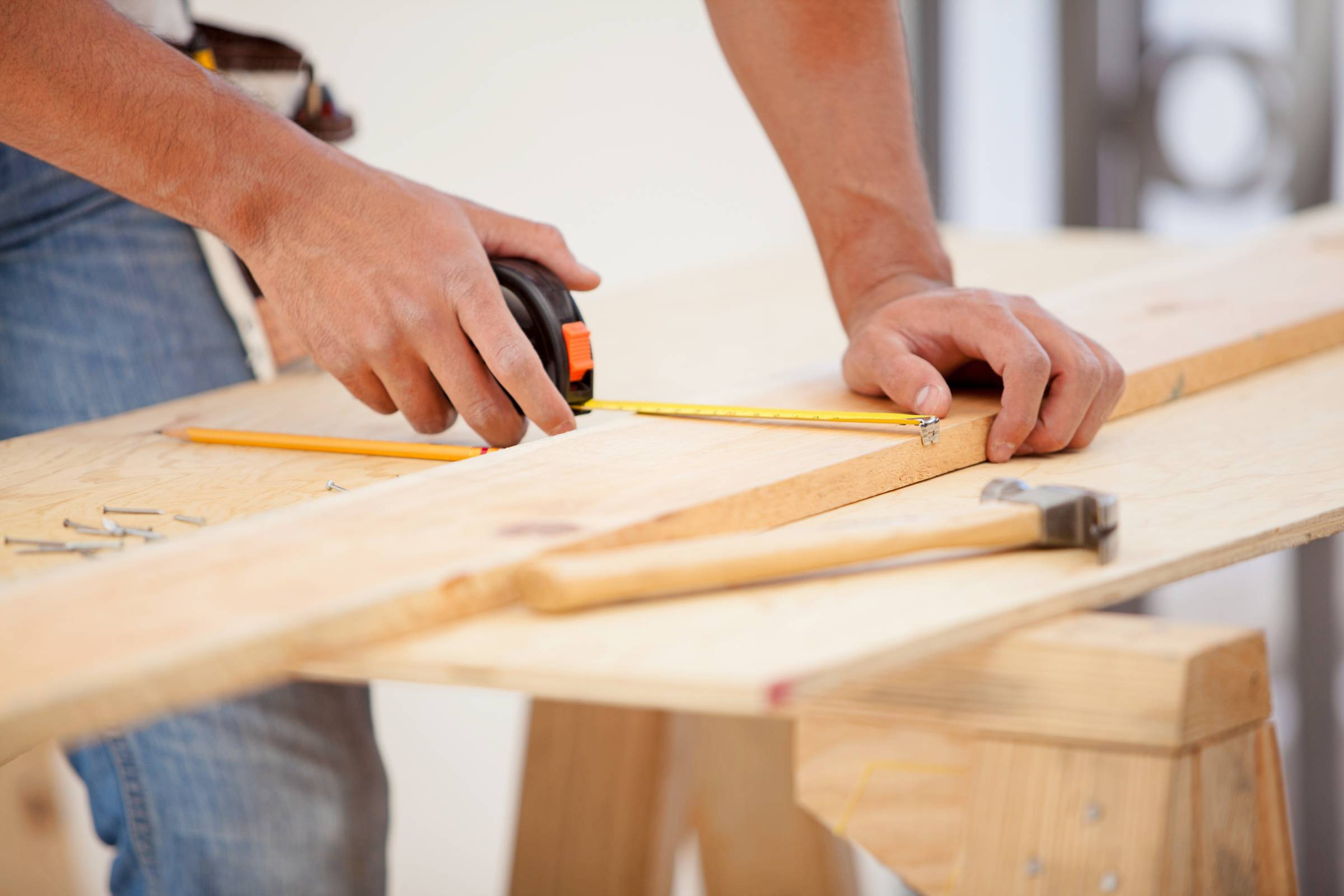 a carpenter using a tape measure