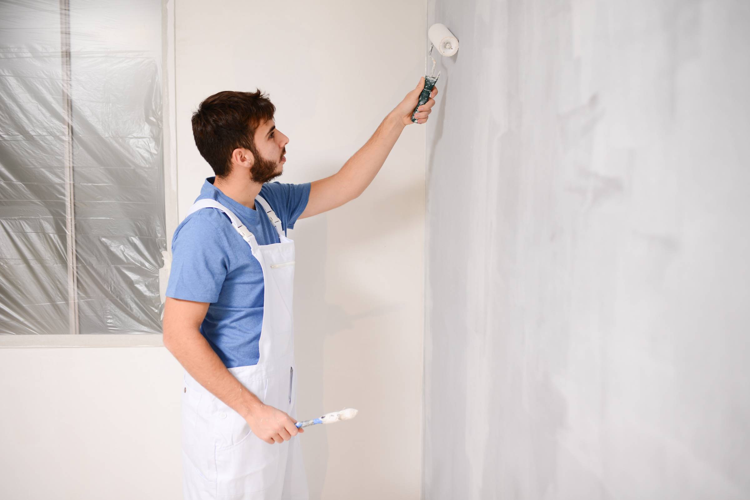 a man painting a wall white