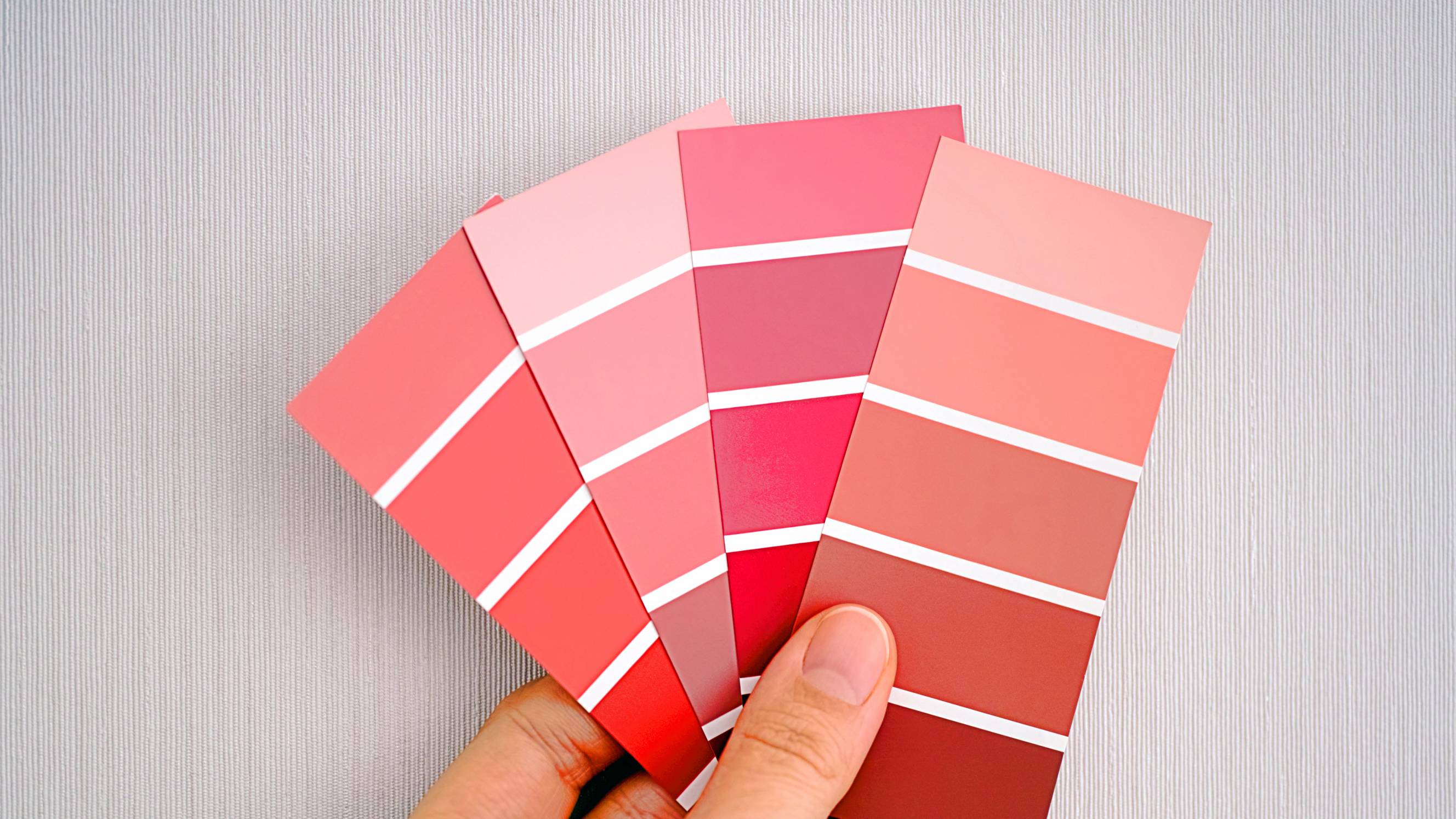 a woman comparing pink paint options for finishing walls