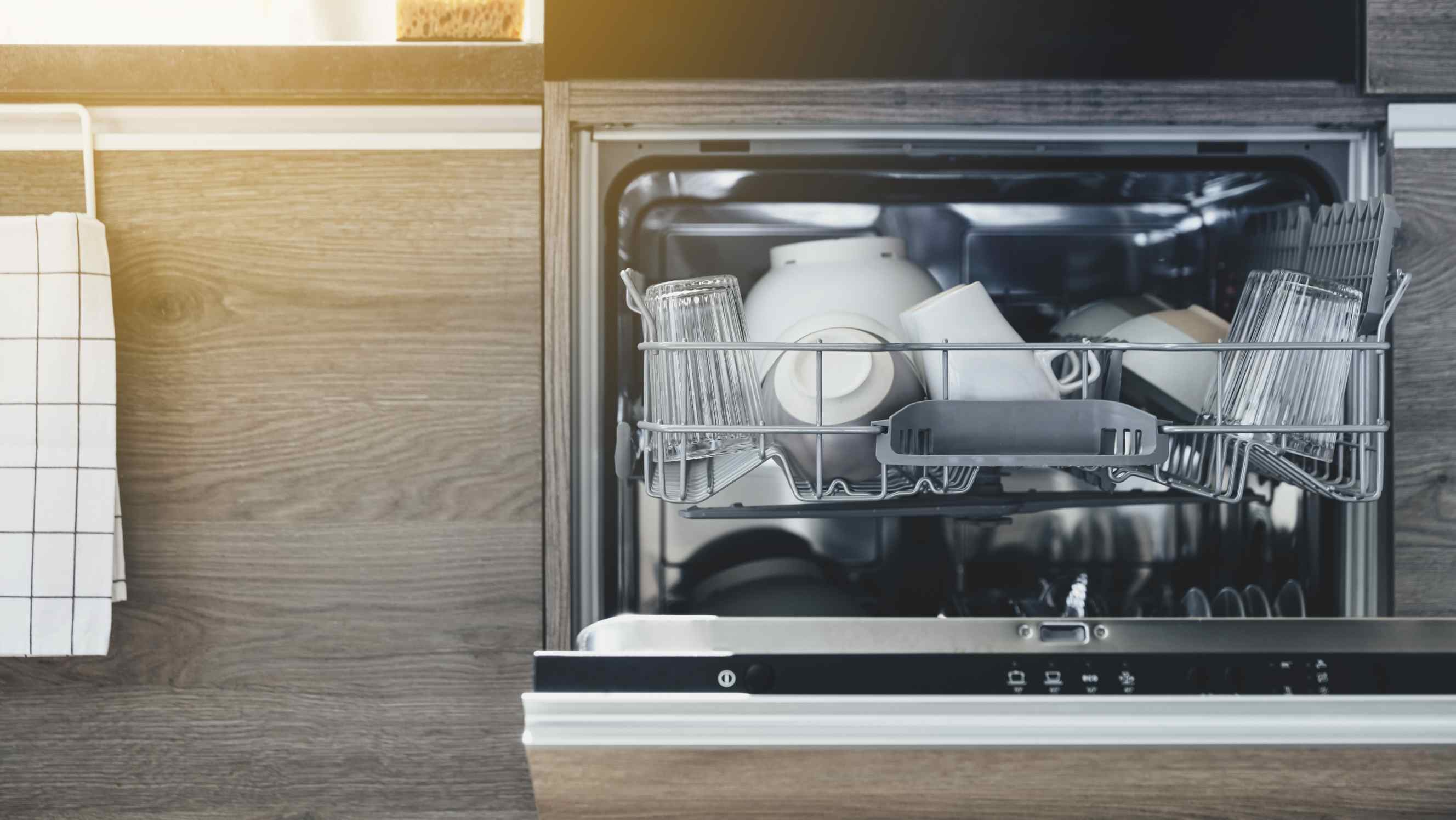 Integrated vs freestanding dishwasher: Close up of opened automatic stainless integrated dishwasher machine
