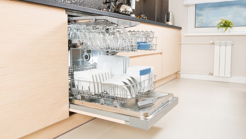 Integrated vs freestanding dishwasher: Open dishwasher with clean utensils in it.