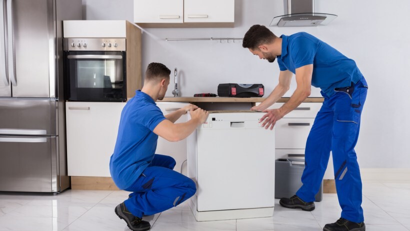 Integrated vs freestanding dishwasher: Two male installing a dishwasher in a someone's kitchen