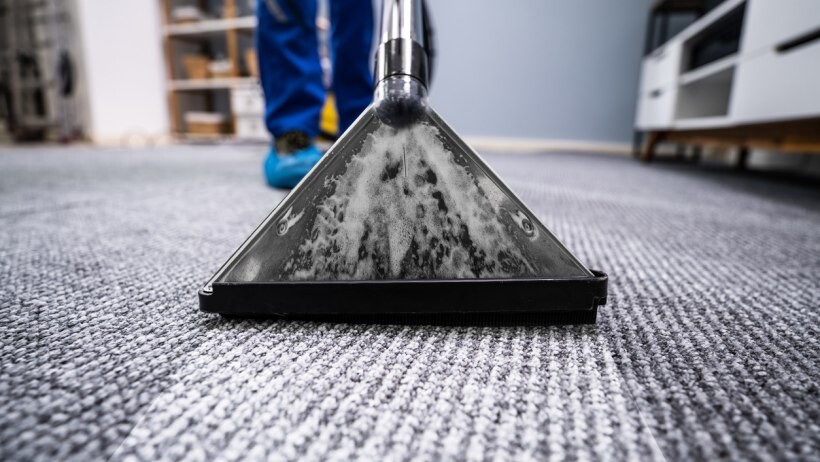 Steam cleaner vs carpet cleaner - a close-up of a person using a carpet cleaner to clean a dirty carpet
