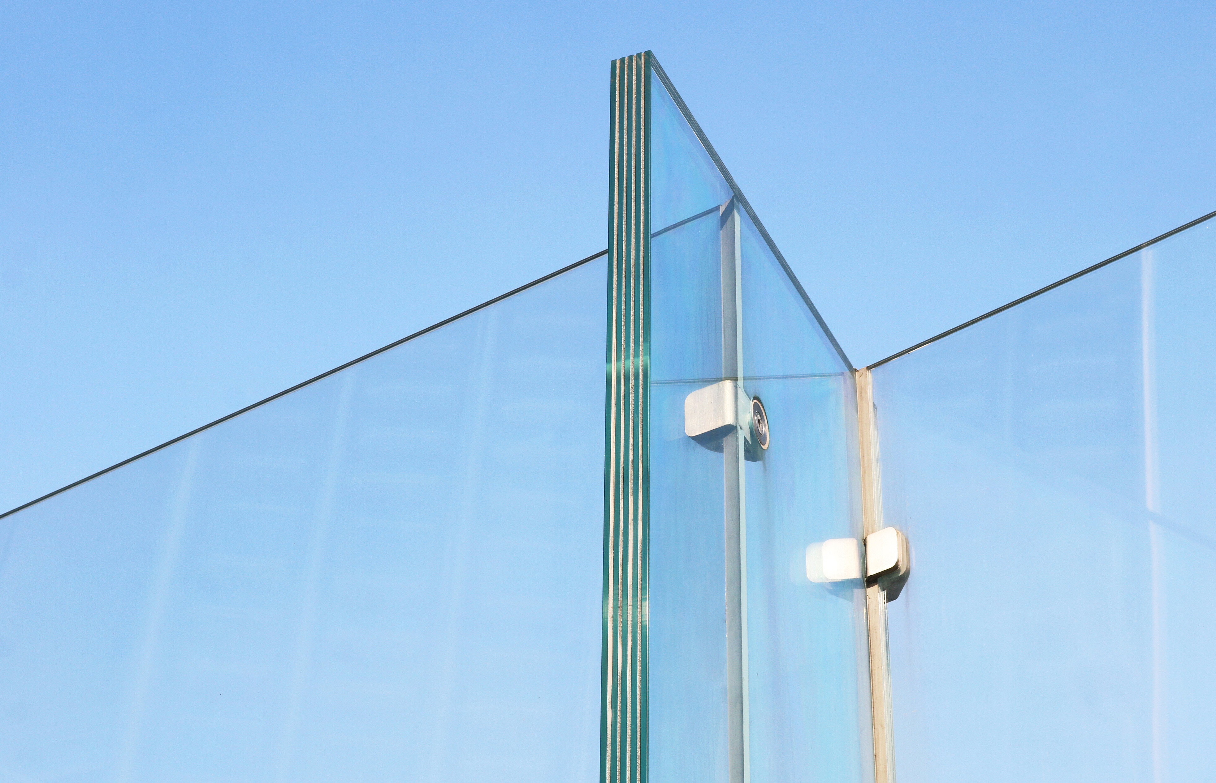 A photo of a clear glass fence against the blue sky.