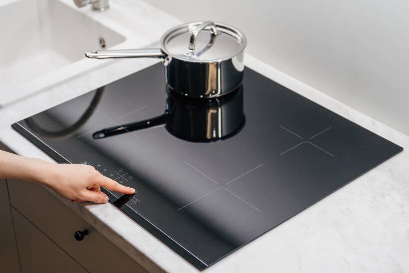 a woman switching on the induction hob - induction vs gas hob