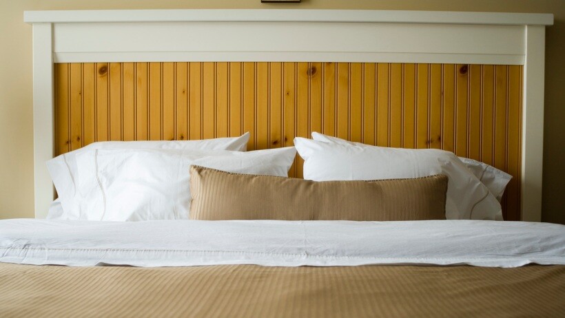 Double bed vs queen bed vs king bed -  A close up of a queen bed with a wooden headboard