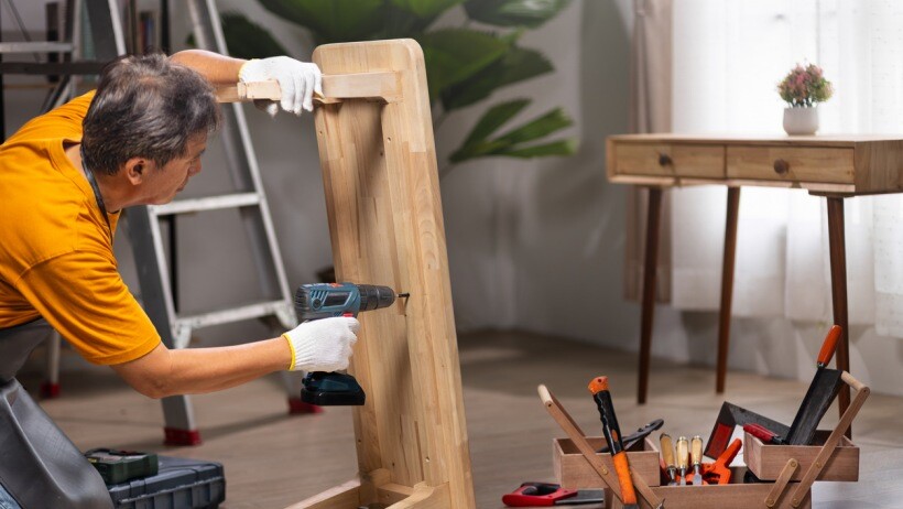 Impact driver vs impact wrench - A handyman repairing a small wooden table using an impact drill