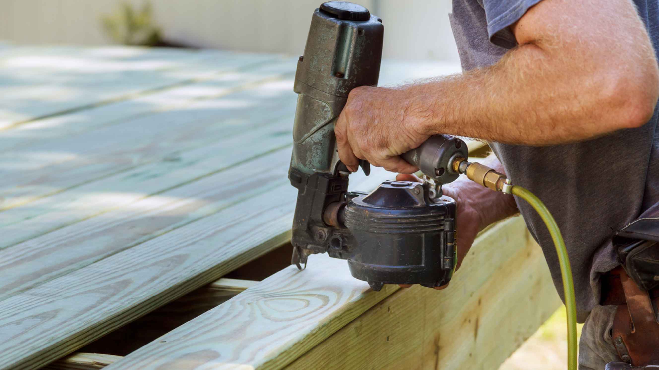 Nail gun vs staple gun - A person installing wood on deck using a nail gun