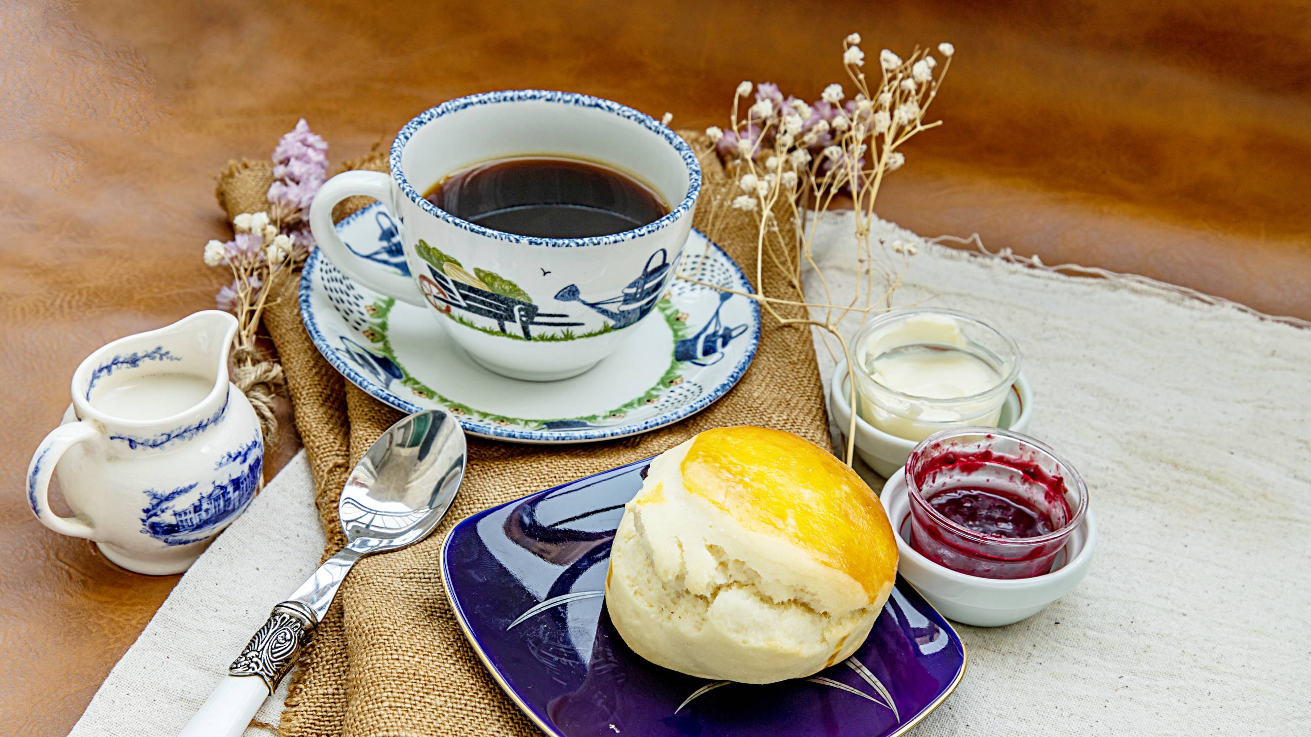 Scones with clotted cream and raspberry jam served with black coffee with milk