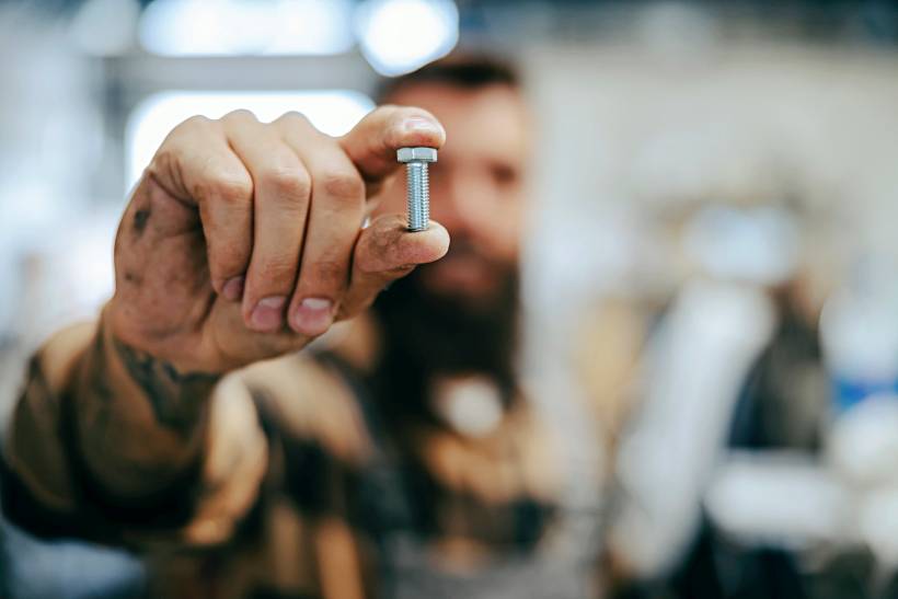 screw vs bolt - a close up of a man holding a screw