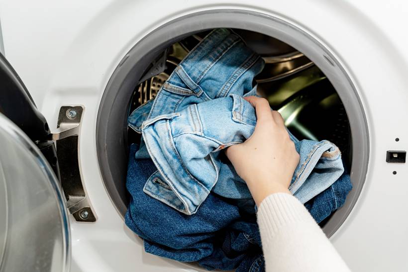 dry cleaning vs washing - a woman putting clothes in a washing machine