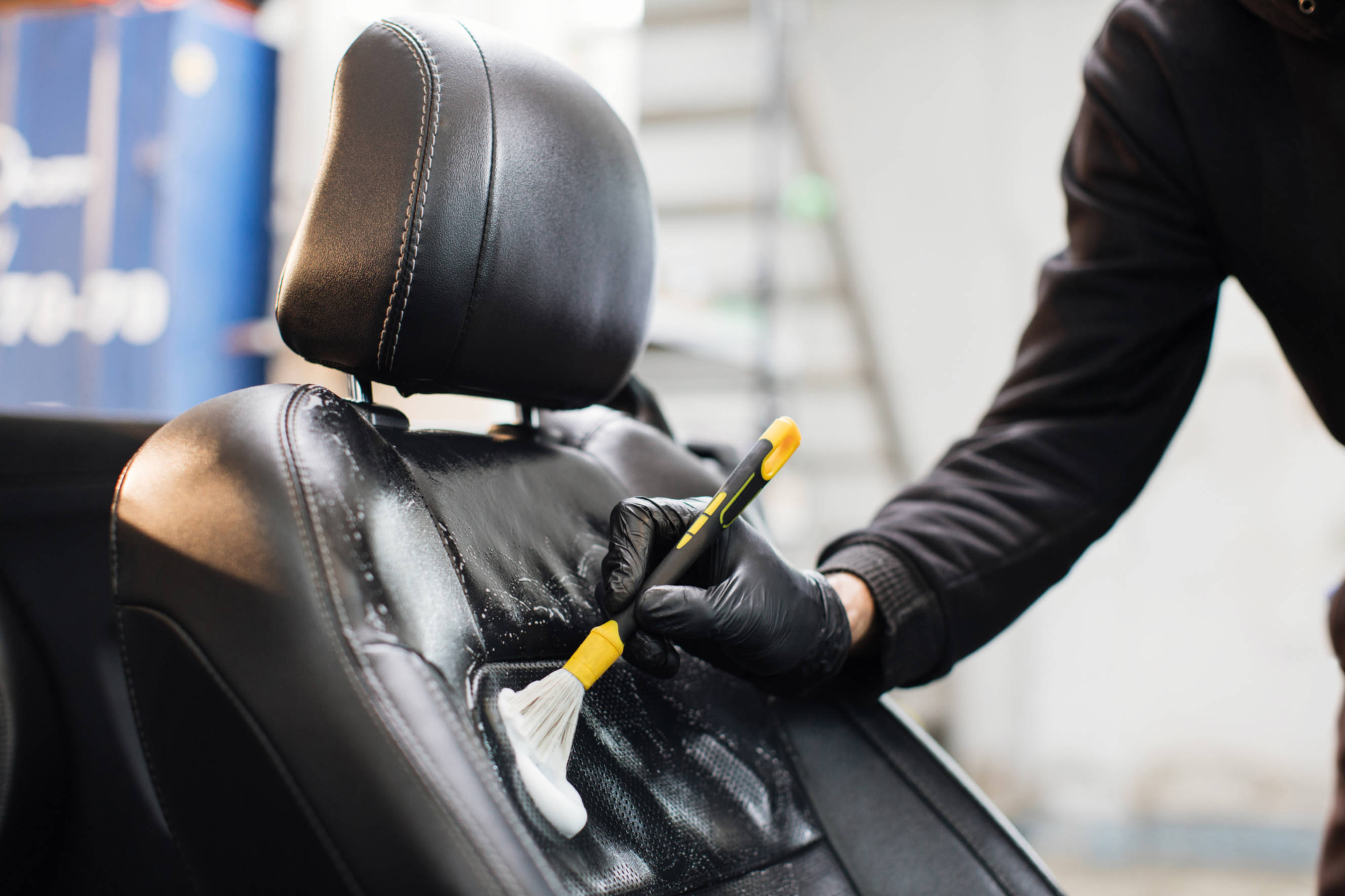 Technician carefully cleaning and restoring a leather car seat during a leather car seat restoration service to improve the vehicle's interior appearance.