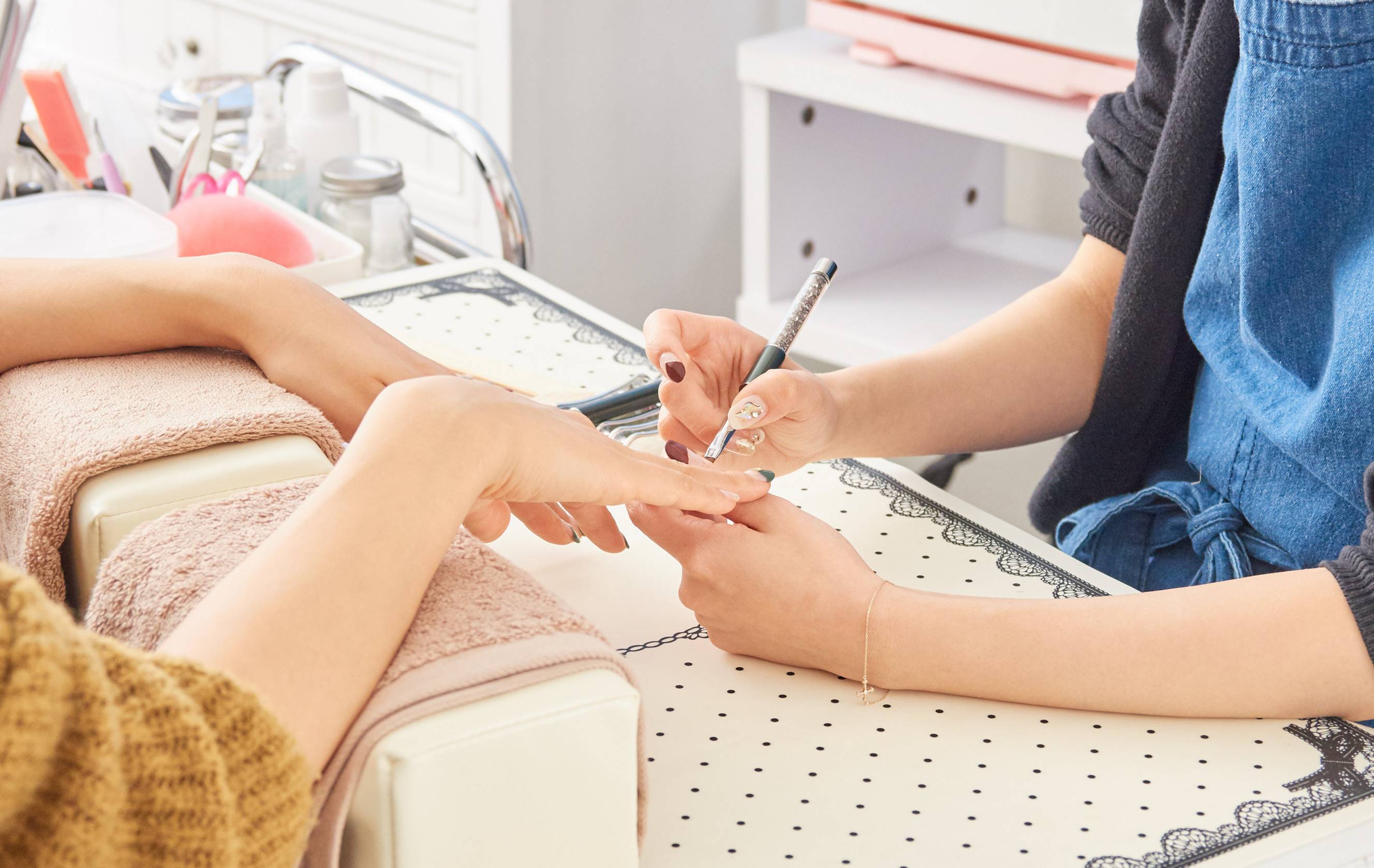 A nail technician performing a home manicure service on a woman's hands.