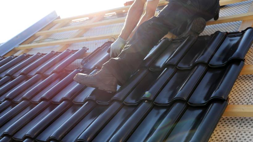 a man installing new roofing on a house - new roof cost