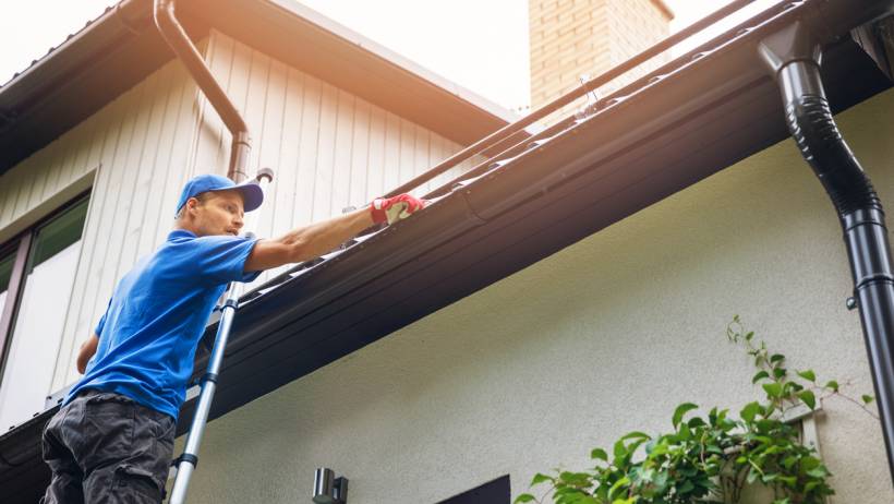 a worker checking the roof gutters - new roof cost