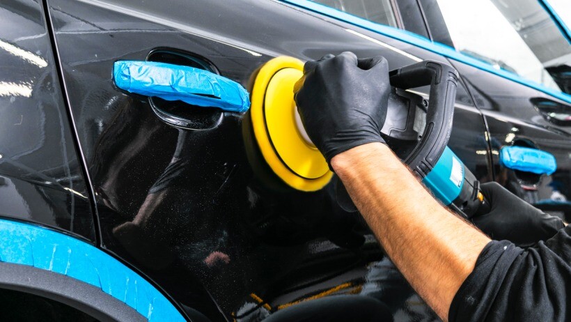 Car polish vs wax - A person's hands, wearing black gloves, using a polishing tool on the exterior of a vehicle