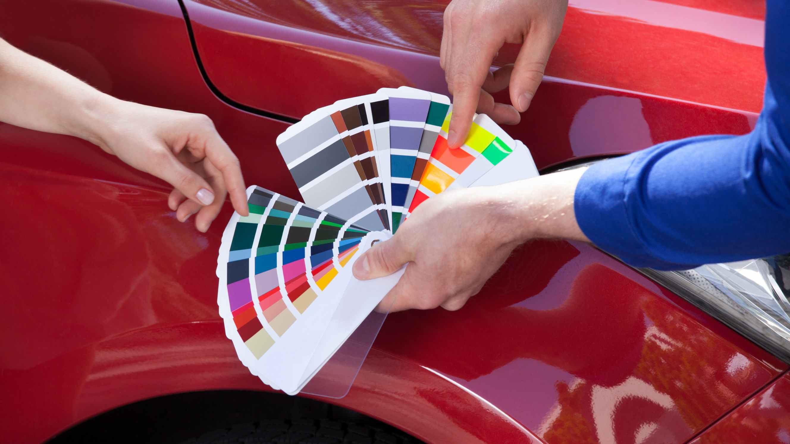 Car wrap vs paint - A person showing color swatches to a red car.