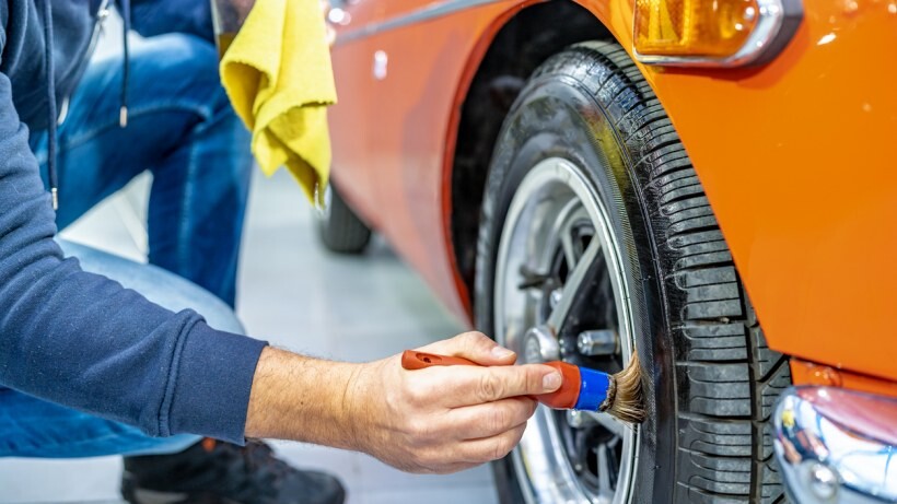 Car detailing vs car wash - A person using a brush to clean a car tyre