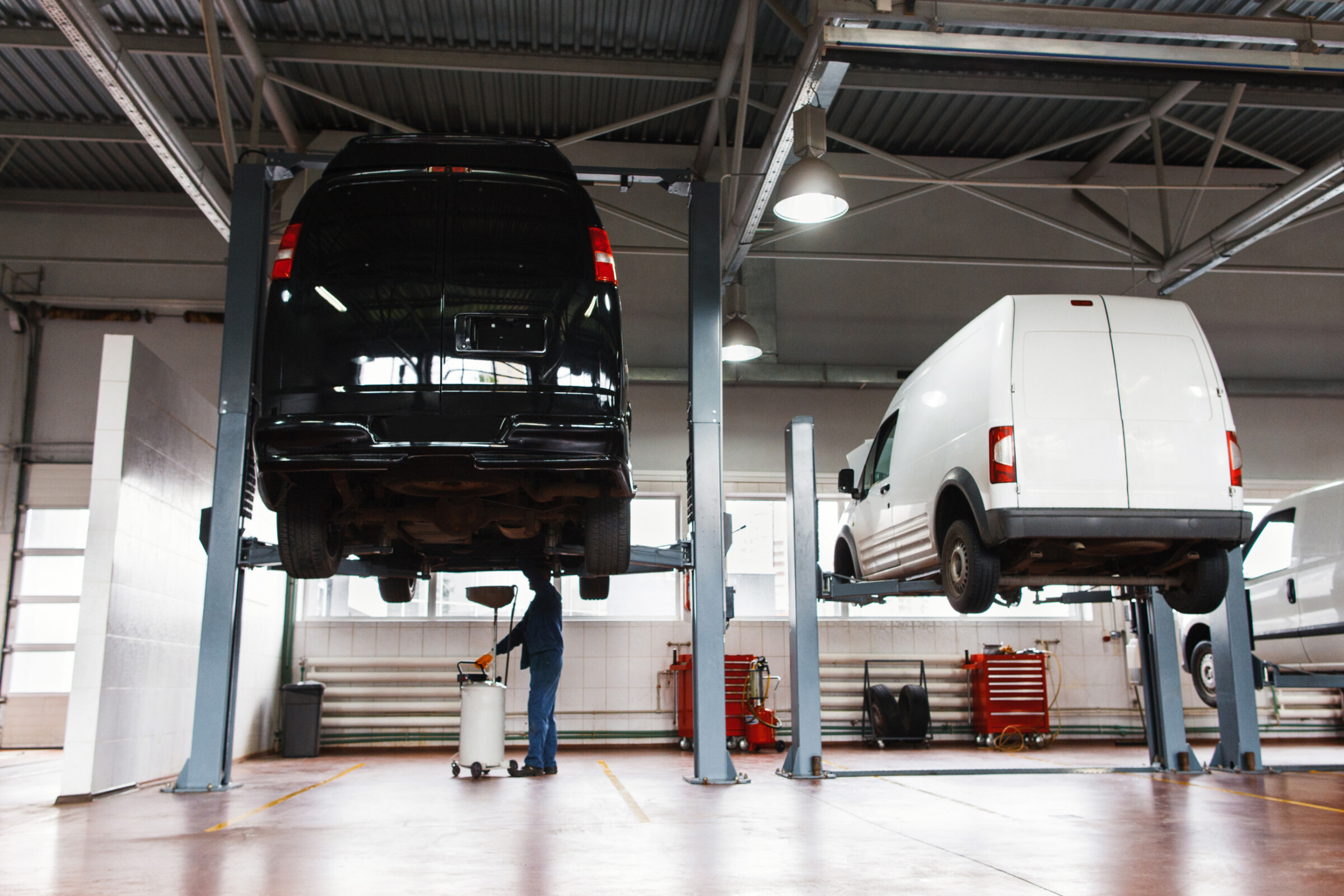 A mechanic inspecting vans in a garage.